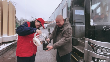 2026年1月1日，风雪天里，身披红色志愿背心的工作人员，在户外为司乘人员提供暖心服务。她笑着将热水缓缓斟入司乘的保温杯，动作细致又热情，简单的举动在冰天雪地中，为赶路的司乘驱散了寒意，也让便民服务的温情在旅途里传递。_副本_副本.jpg
